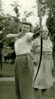 Women practicing archery,blond woman with banana curls in foreground